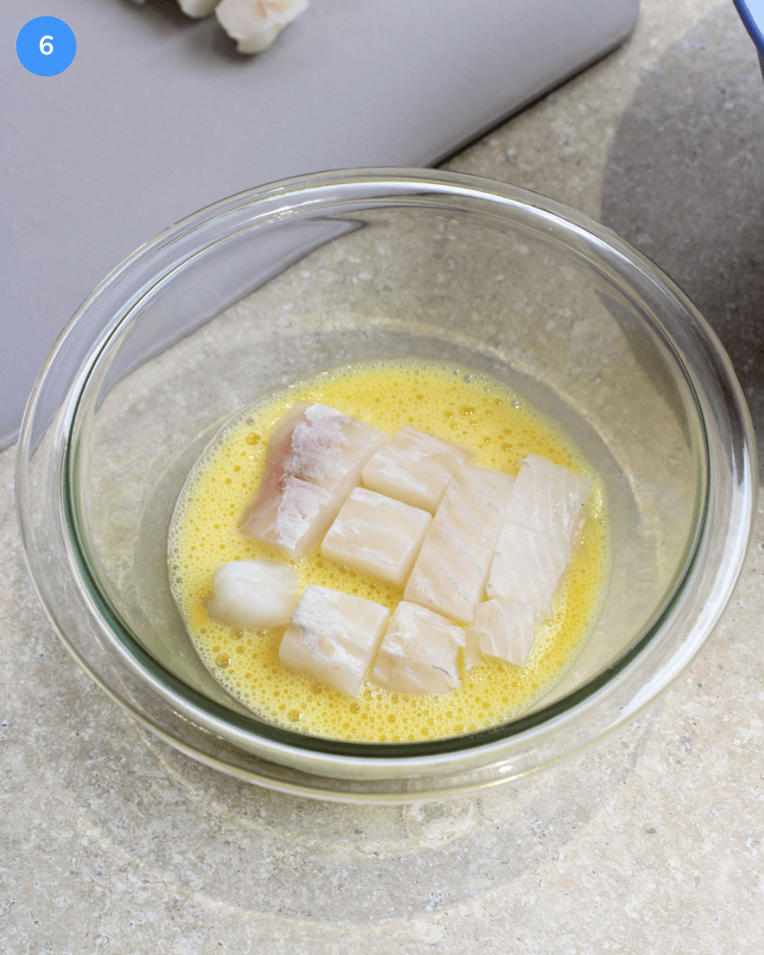 Step 6 of making fried fish tacos. Cubes of cod being dipped into and coated with egg.