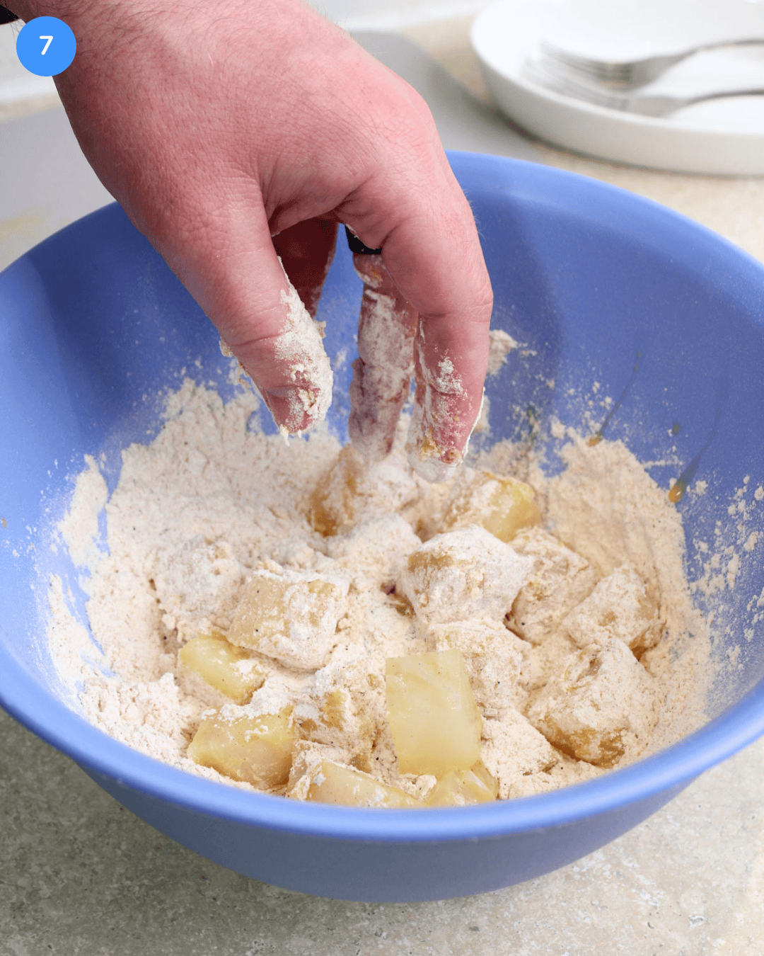 Step 7 of making fried fish tacos. Cod that has been dipped in egg being dredged in a flour and seasoning mixture.