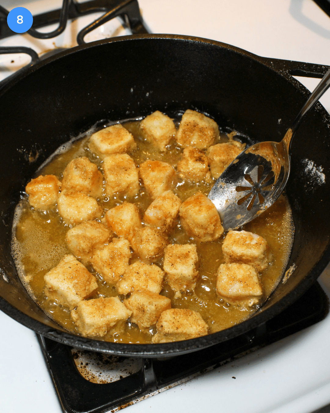 Step 8 of making fried fish tacos. Floured cod being deep fried in a deep cast iron pan.