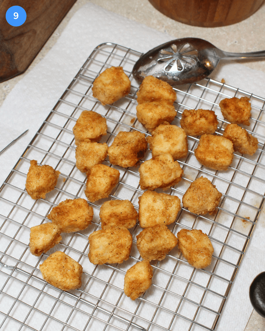 Step 9 for making fried fish tacos. Fried cubes of cod on a cooling rack.