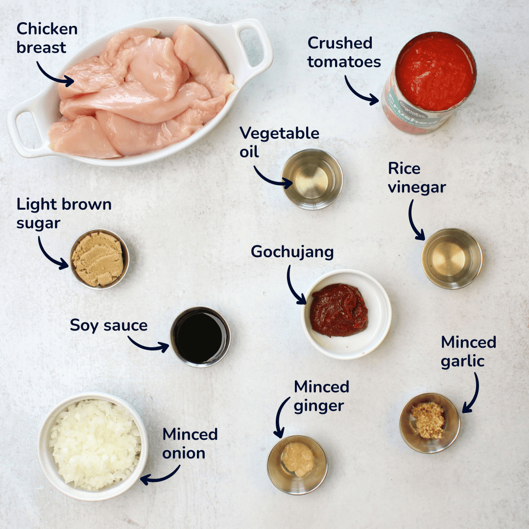 Ingredients for making gochujang chicken: chicken breast, crushed tomatoes, vegetable oil, rice vinegar, gochujang, soy sauce, light brown sugar, minced onion, minced ginger, and minced garlic.