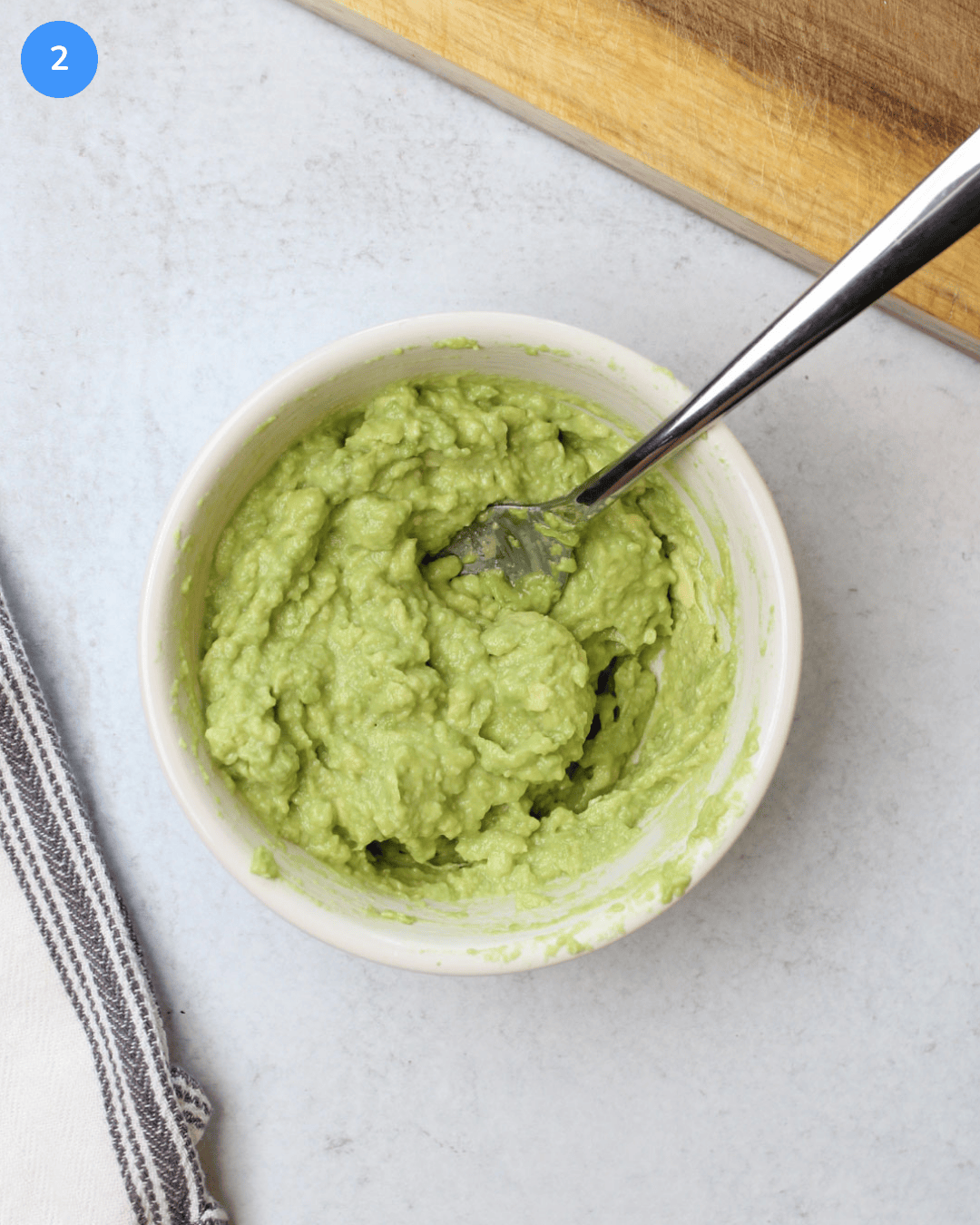 A small ceramic bowl of mashed avocado with lime juice and salt.