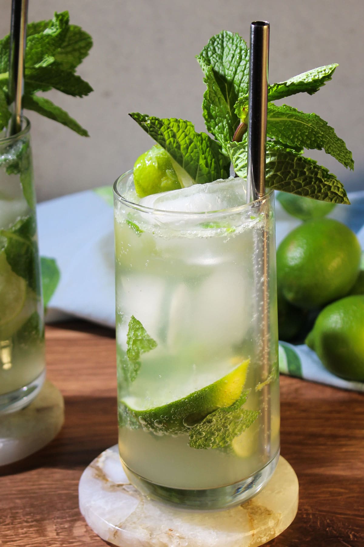 A bubbly mojito mocktail served in a tall glass with a straw and fresh mint sprig garnish.