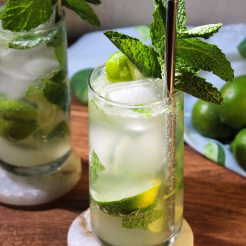 Two mojito mocktails served in tall glasses with fresh mint sprigs.