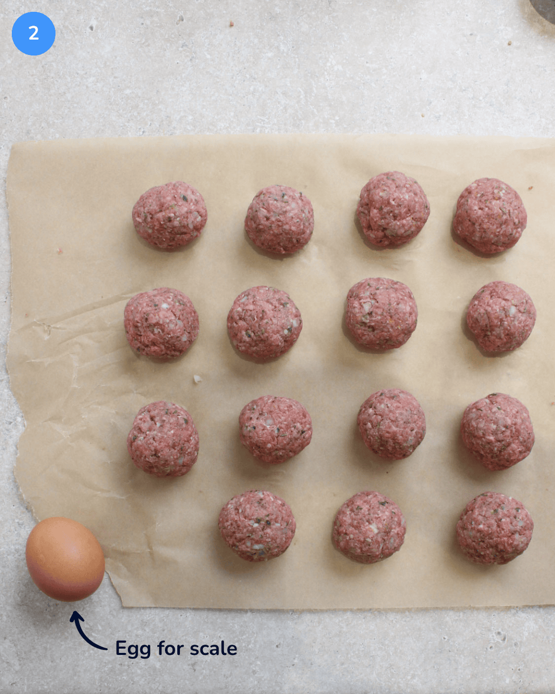 Step 2: Raw meatballs rolled and laid out on parchment paper.