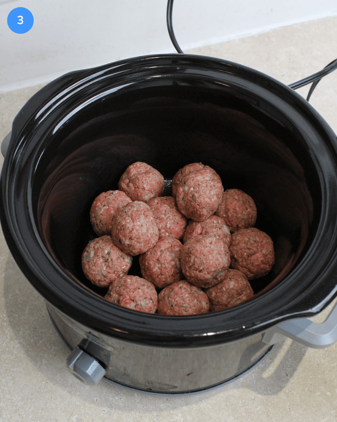 Step 3: Raw meatballs piled into a slow cooker.