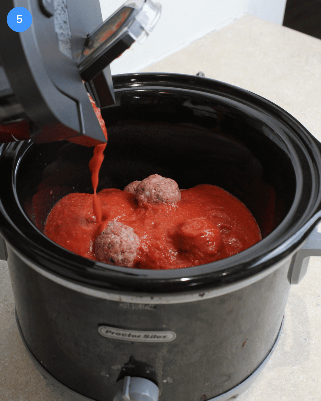 Step 5: pasta sauce being poured over raw meatballs in a slow cooker.