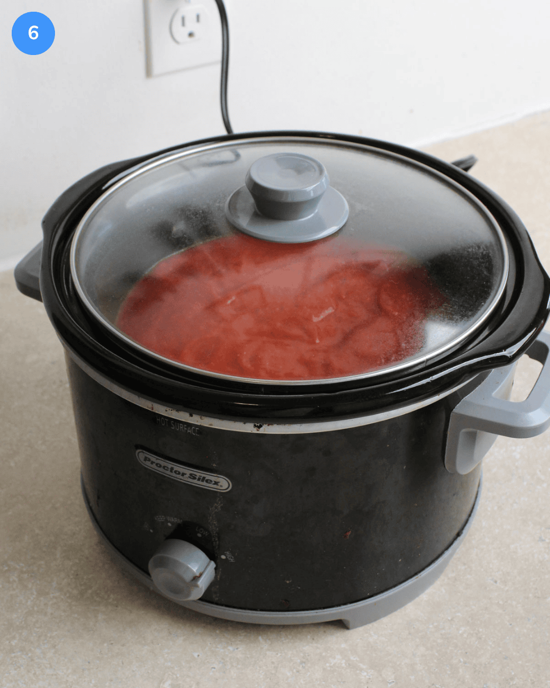 Step 6: a slow cooker with sauce and meatballs inside cooking .