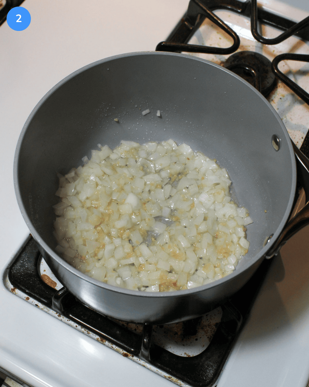 Step 2: A sauce pot of minced garlic and chopped white onion being sauteed.