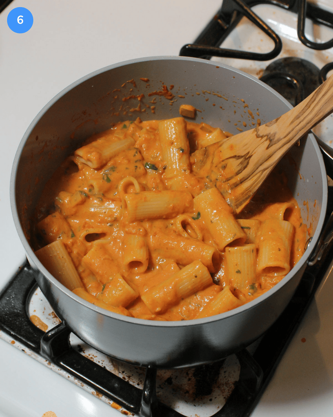 Step 6: A sauce pot filled with cooked rigatoni coated in a creamy, light red tikka masala sauce.