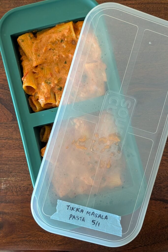A green Souper Cubes freezer tray with freshly made tikka masala pasta in it.