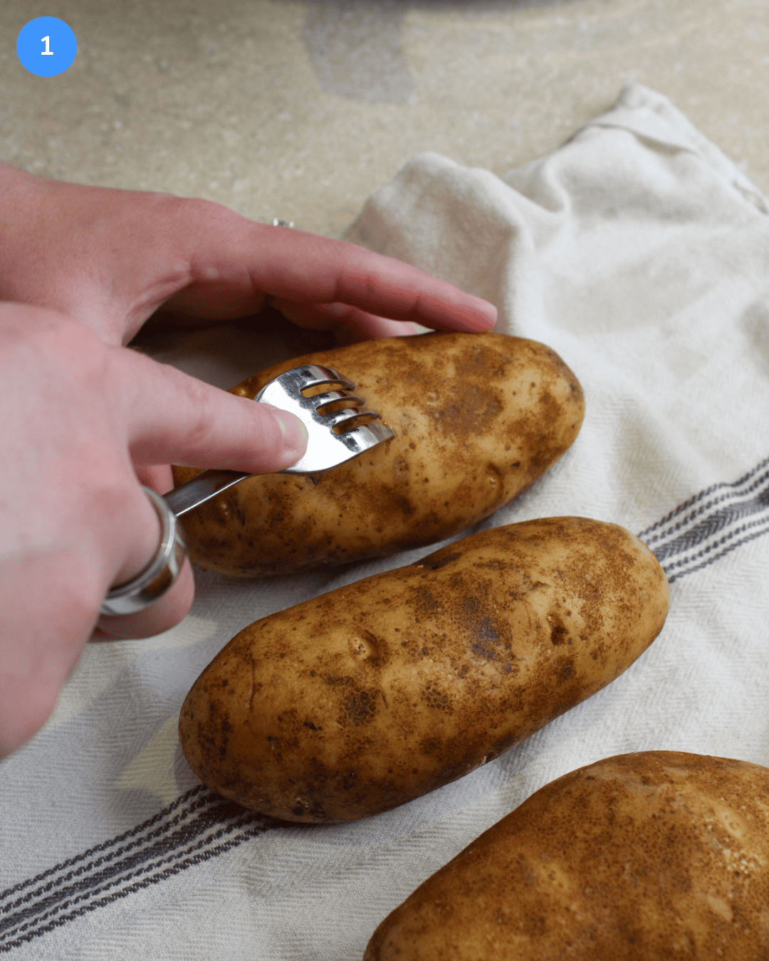 Step 1: Russet potatoes being stabbed with a fork to create air holes.