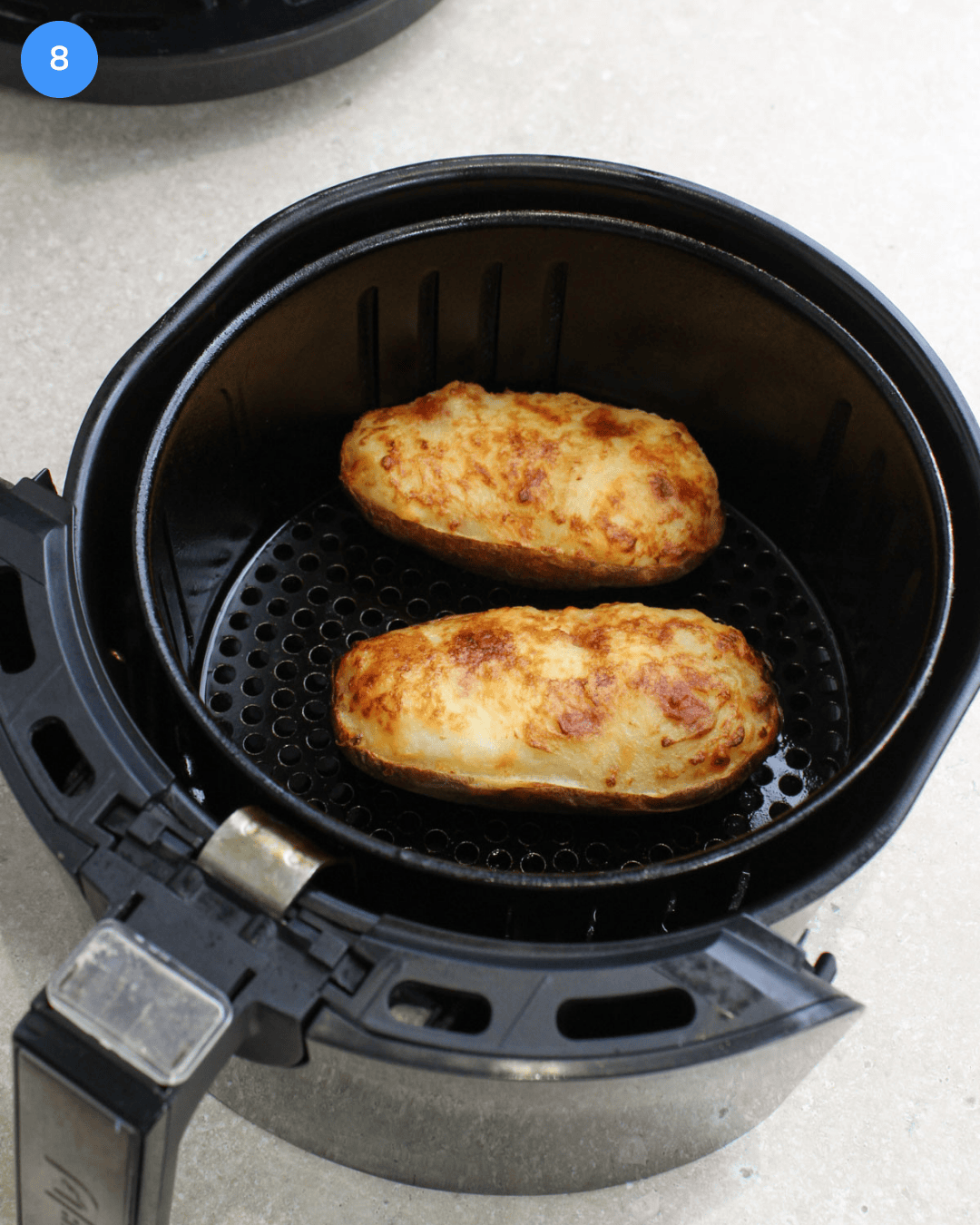Step 8: Two crispy, golden brown, twice air fried potatoes in an air fryer basket.