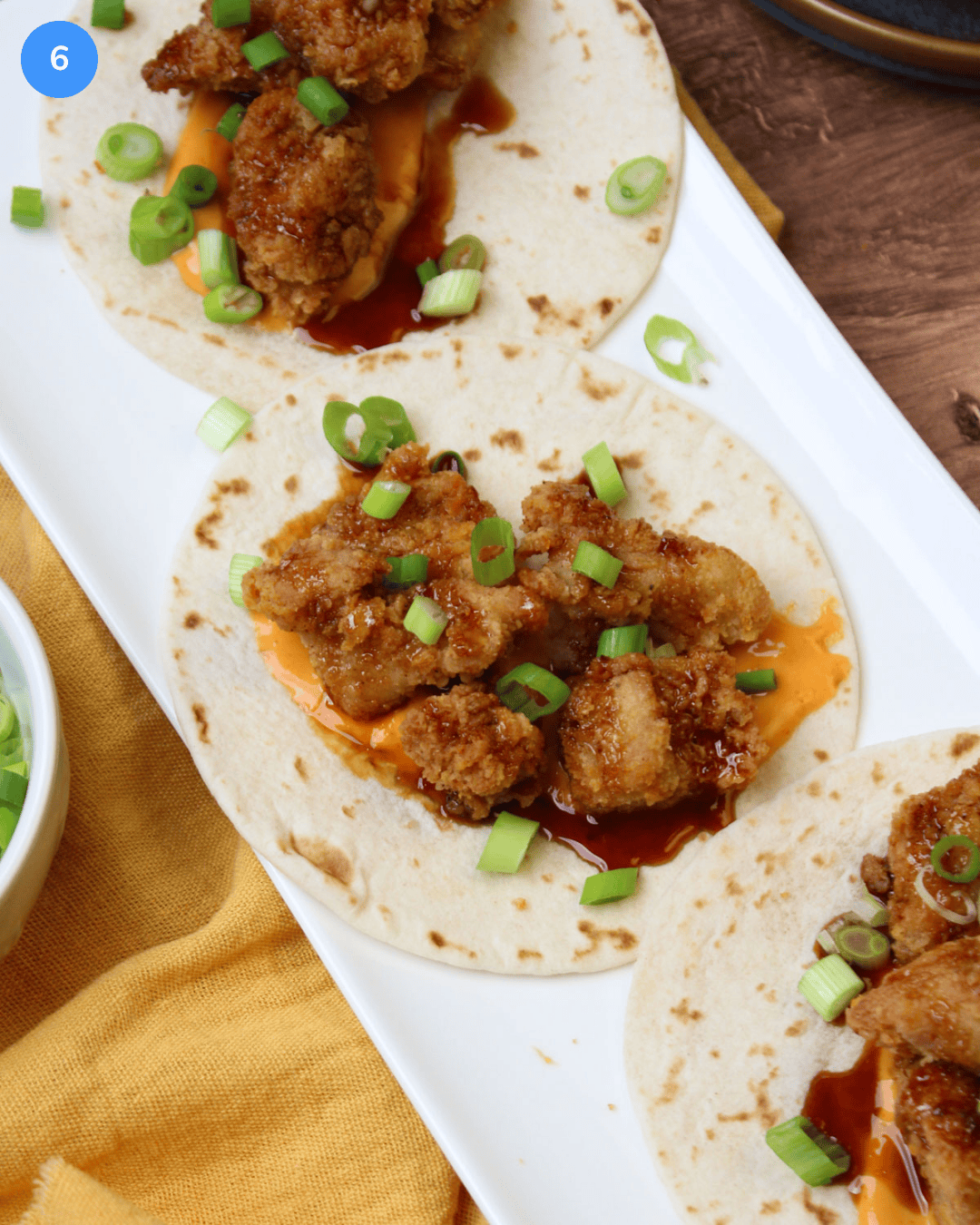 Step 6 of crispy chicken tacos. Freshly made Asian fried chicken tacos with sriracha aioli, sesame soy glaze, and scallions.