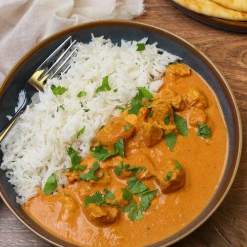 A freshly made bowl of crockpot chicken tikka masala served with basmati rice and naan.
