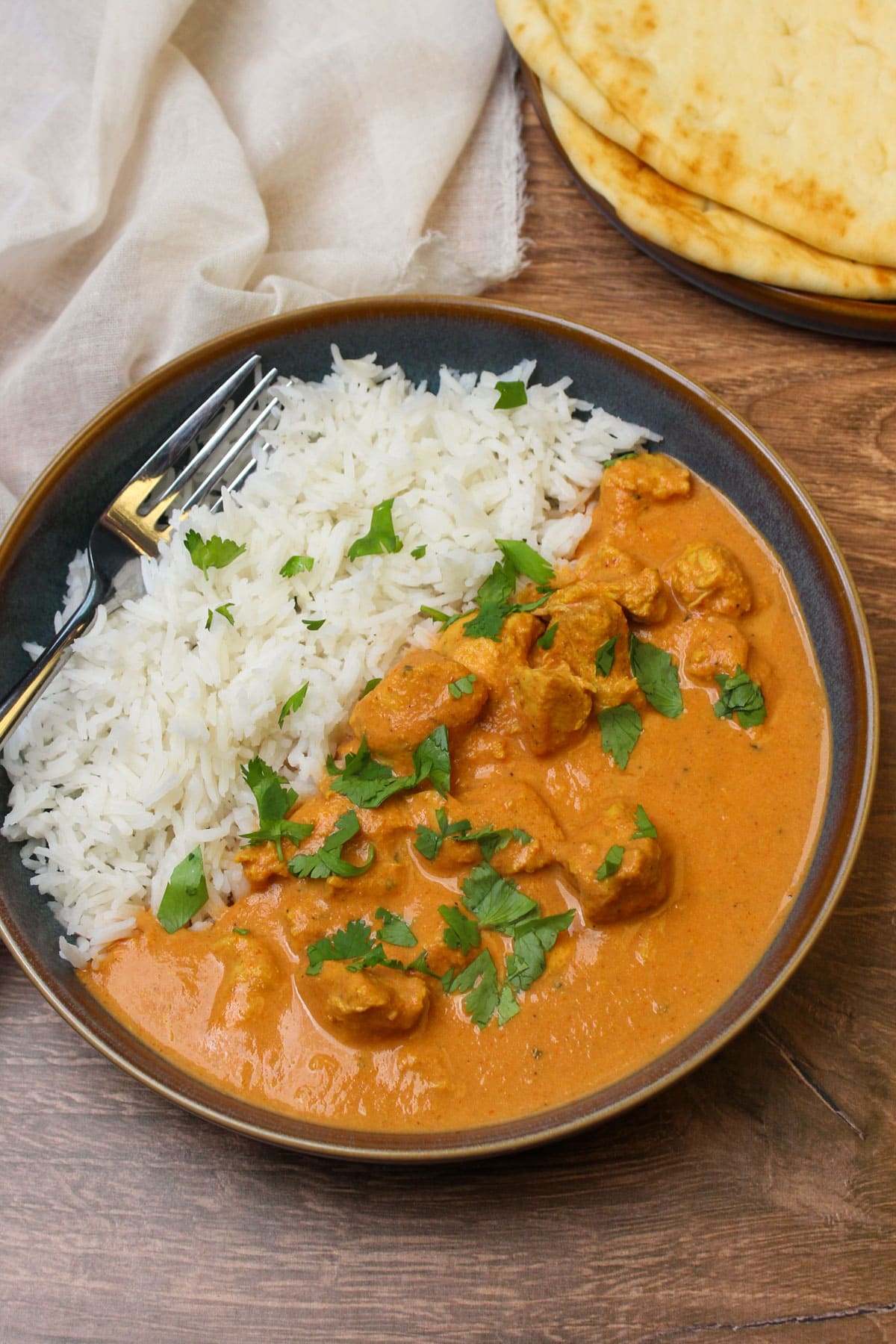 A freshly made bowl of crockpot chicken tikka masala served with basmati rice and naan.