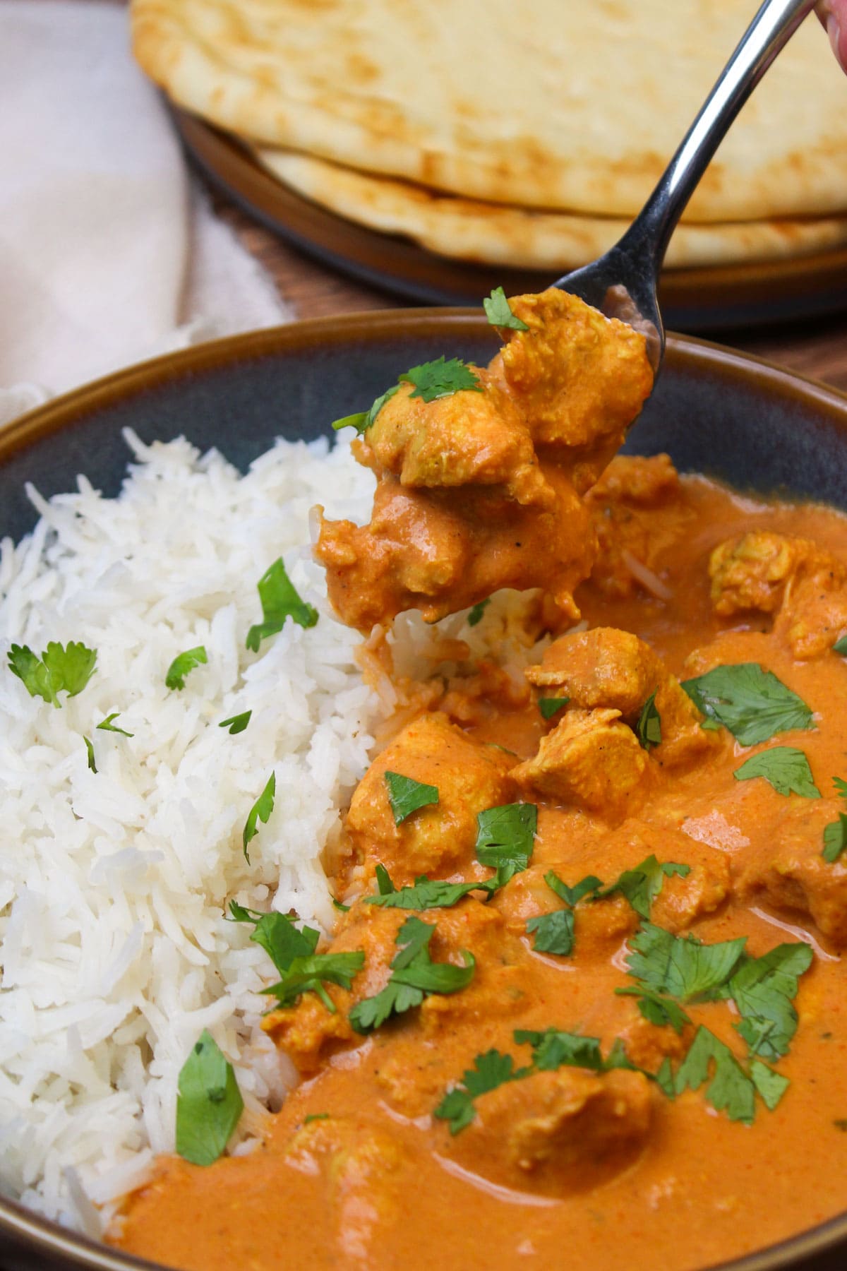 A forkful of homemade chicken tikka masala, served with basmati rice.