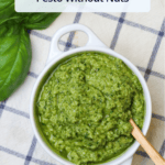 A white ceramic crock of freshly made pesto with a wooden serving spoon with a title overlaid.
