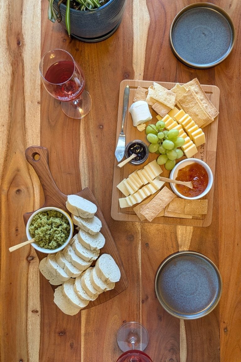 A charcuterie board on a wooden table with small blue serving plates.