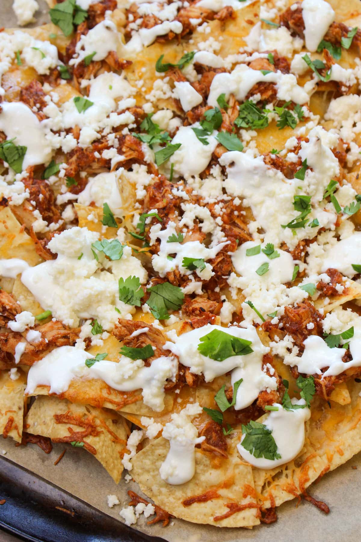 Nachos made with mexican cheese, chicken tinga, queso fresco, lime crema, and cilantro.