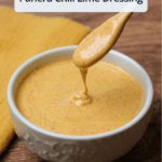 A white ceramic bowl of chili lime salad dressing drizzling off a wooden spoon with a title overlaid.