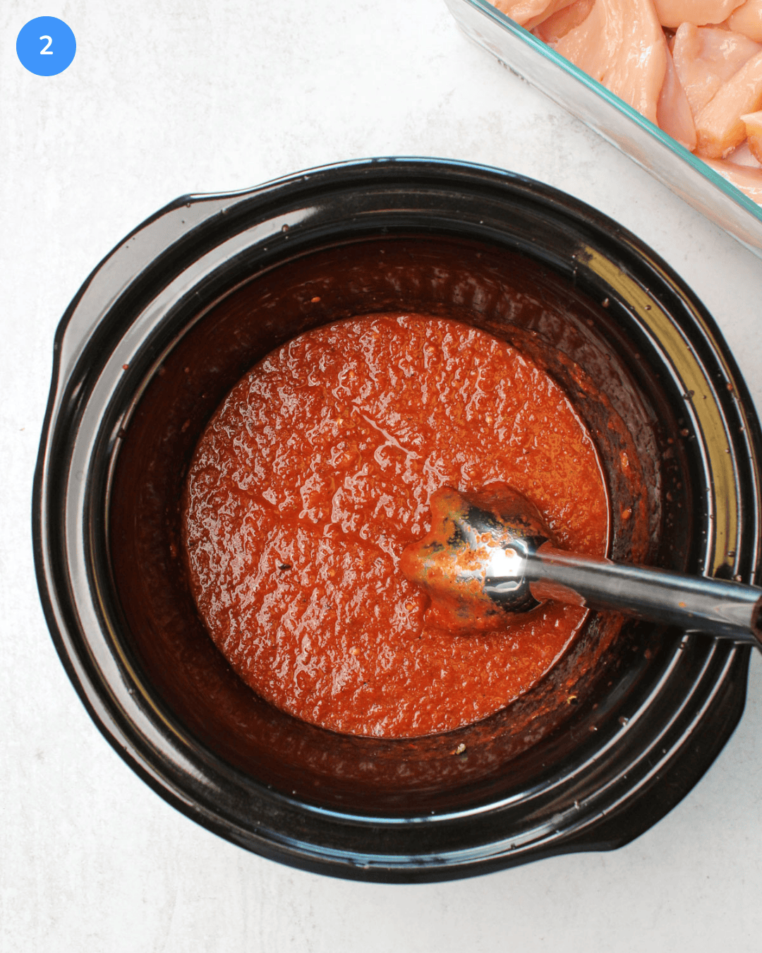 How to make crockpot chicken tinga step 2: All the ingredients have been blended in the crockpot with an immersion blender to make a bright red sauce.