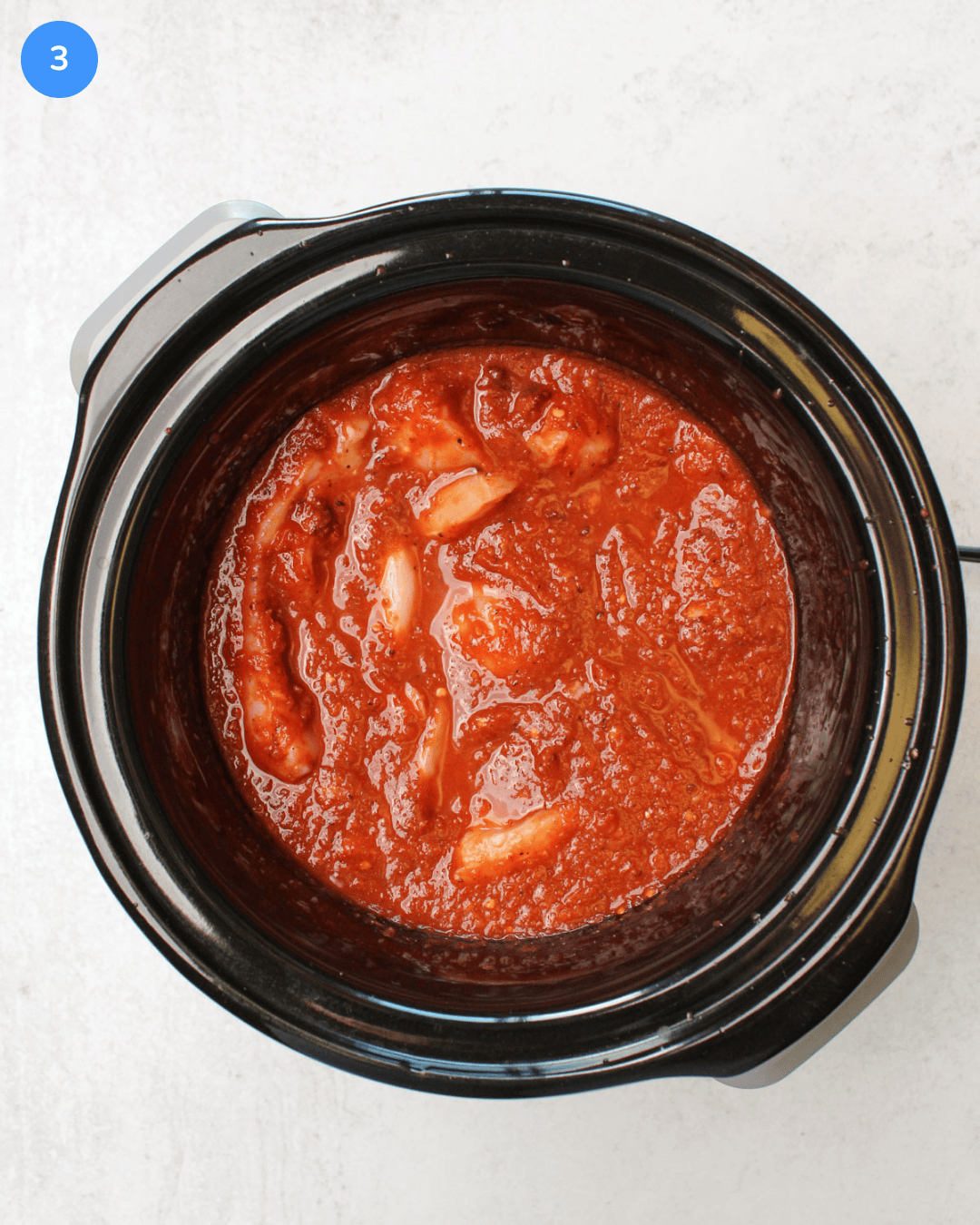 How to make crockpot chicken tinga step 3: Chicken is added to the sauce in the crockpot.