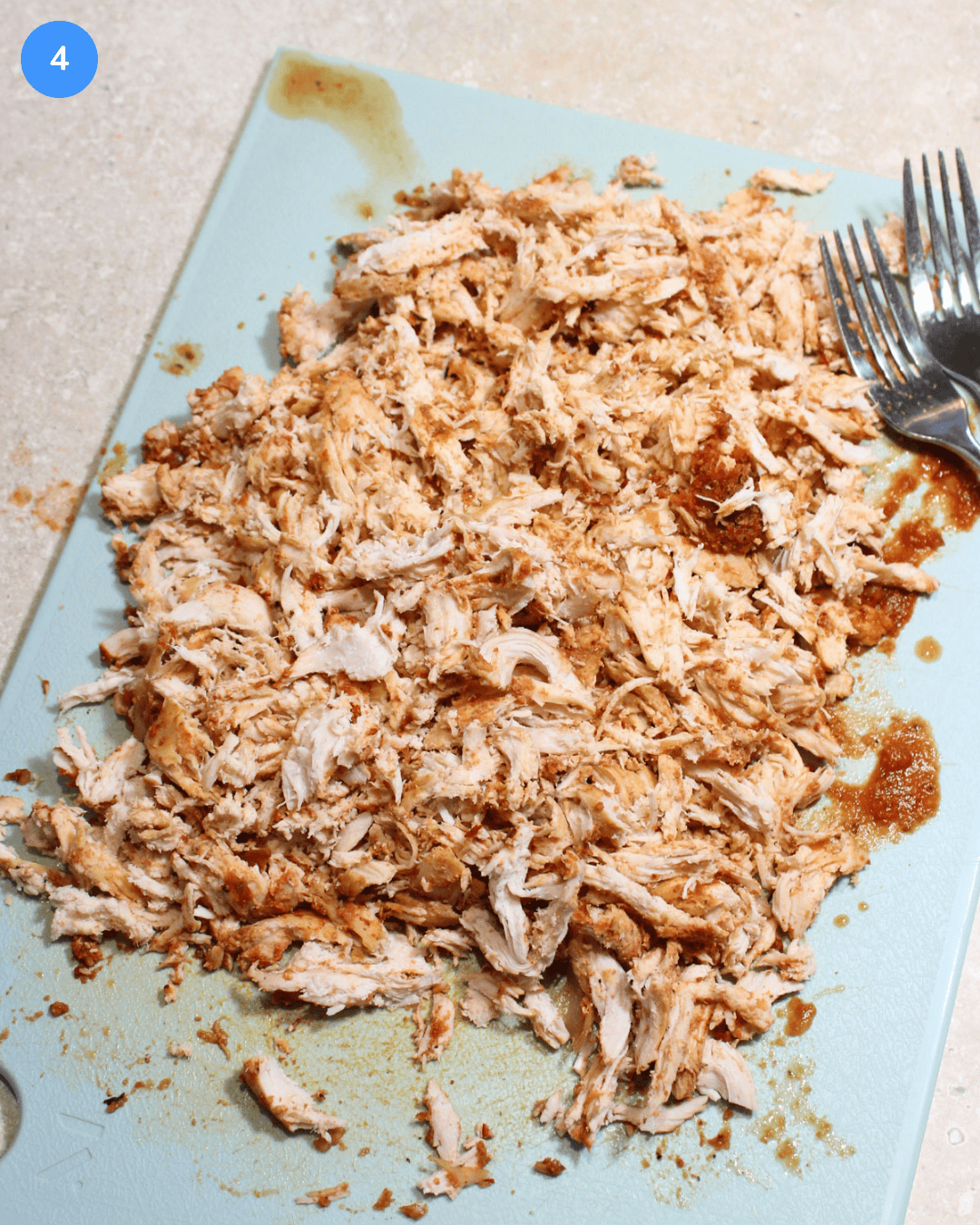 How to make crockpot chicken tinga step 4: once the chicken is cooked, it is removed from the crockpot and shredded on a cutting board.
