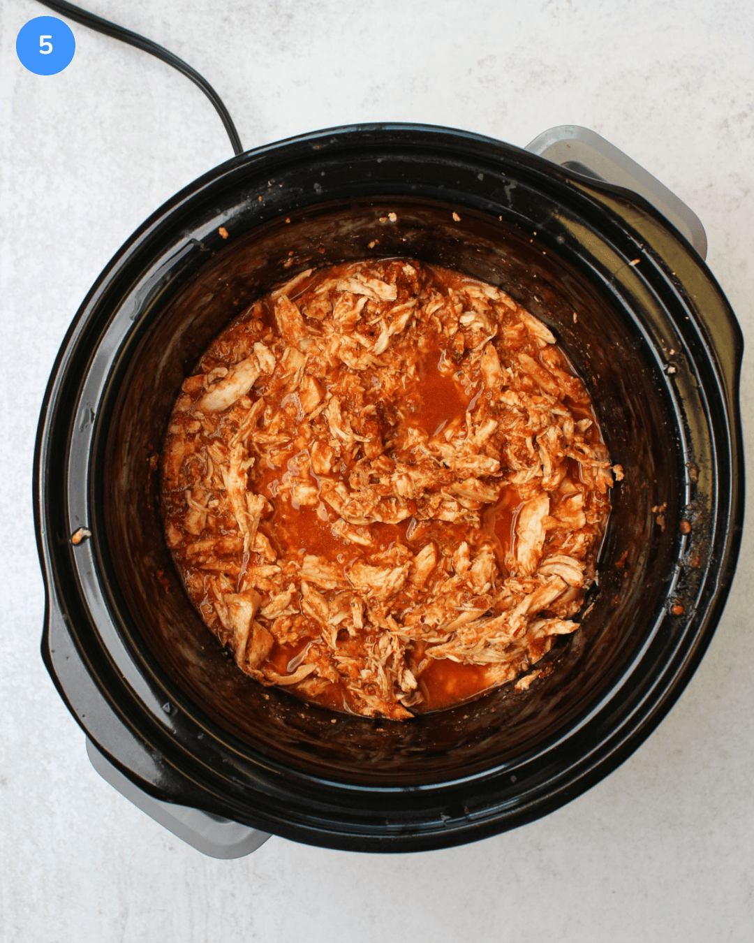 How to make crockpot chicken tinga step 5: The shredded chicken is added back into the crockpot.