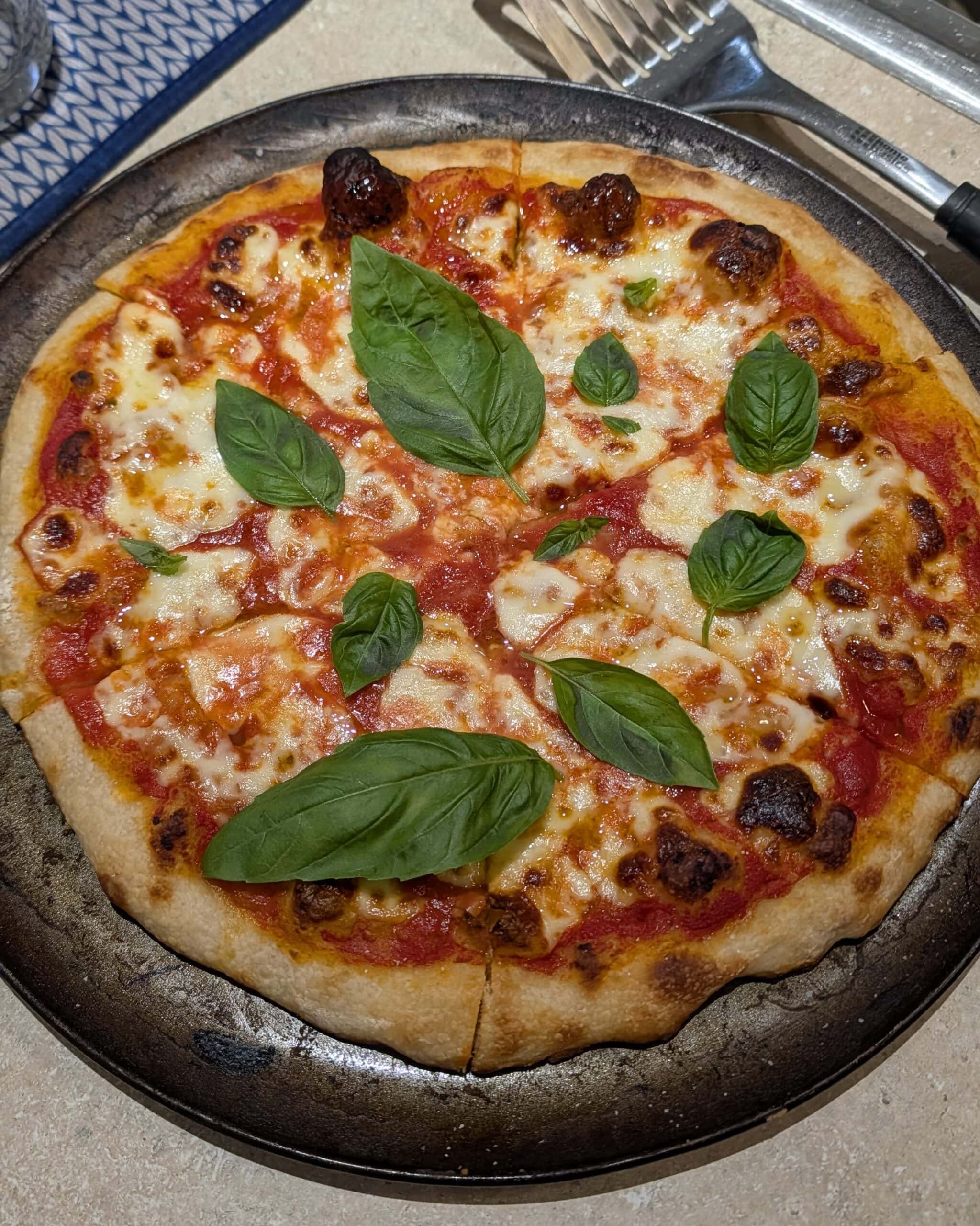 A freshly baked margherita pizza garnished with fresh basil leaves.
