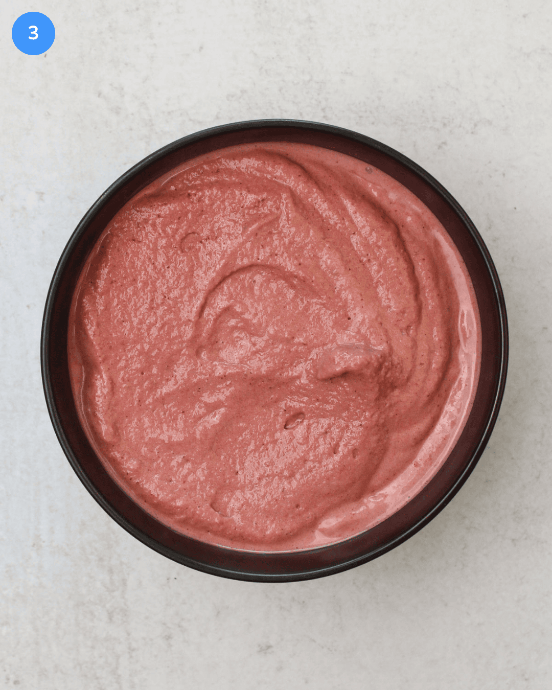 A black stone bowl filled with freshly blended acai smoothie bowl.
