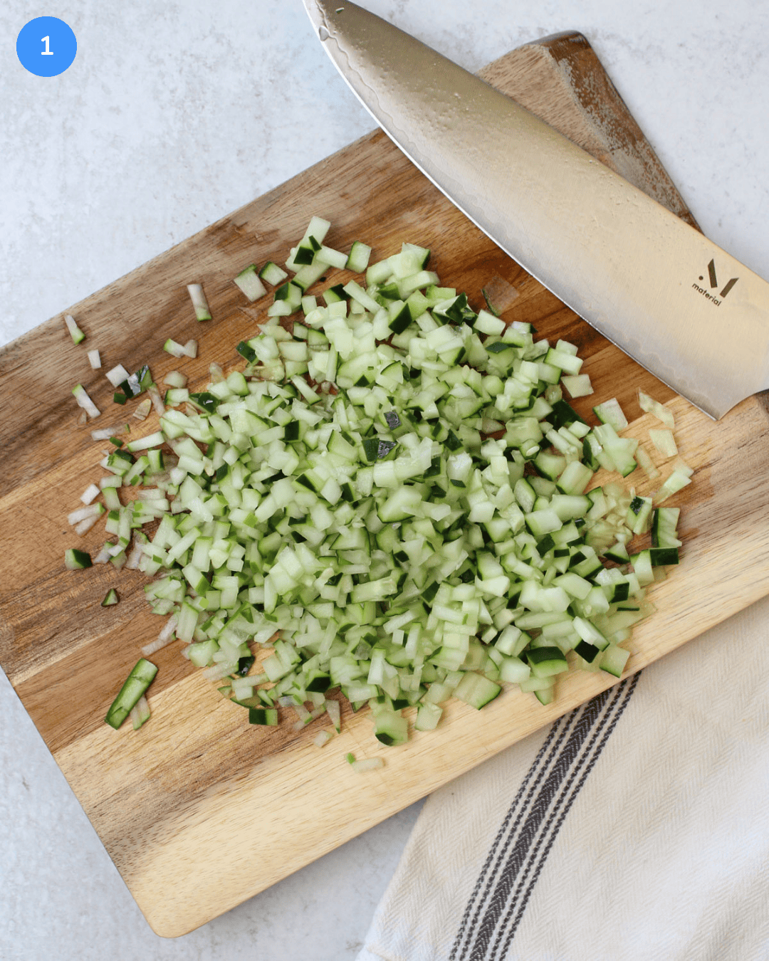 Finely diced cucumber on a wooden cutting board.