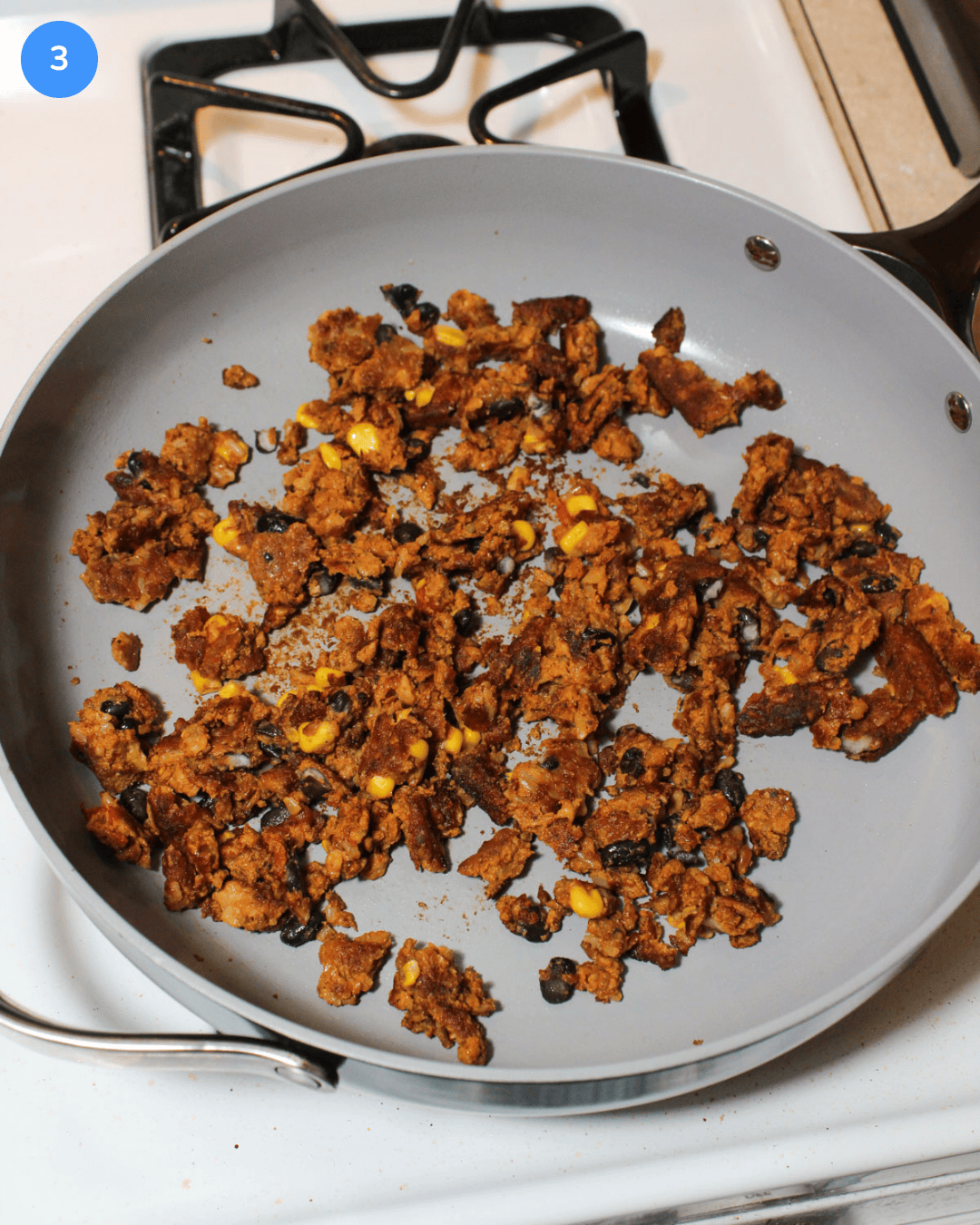 Chopped up black bean burger patties in a saute pan on the stove.