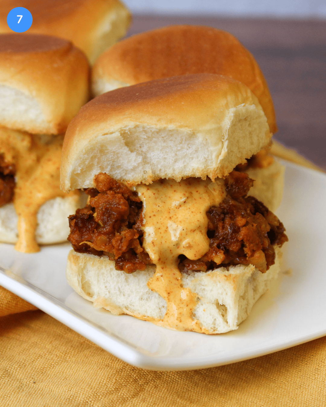A southwest black bean slider with chili lime dressing on a hawaiian roll served on a white ceramic plate.