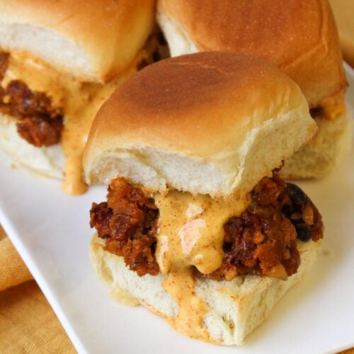 A white plate of southwest black bean sliders with chili lime dressing.