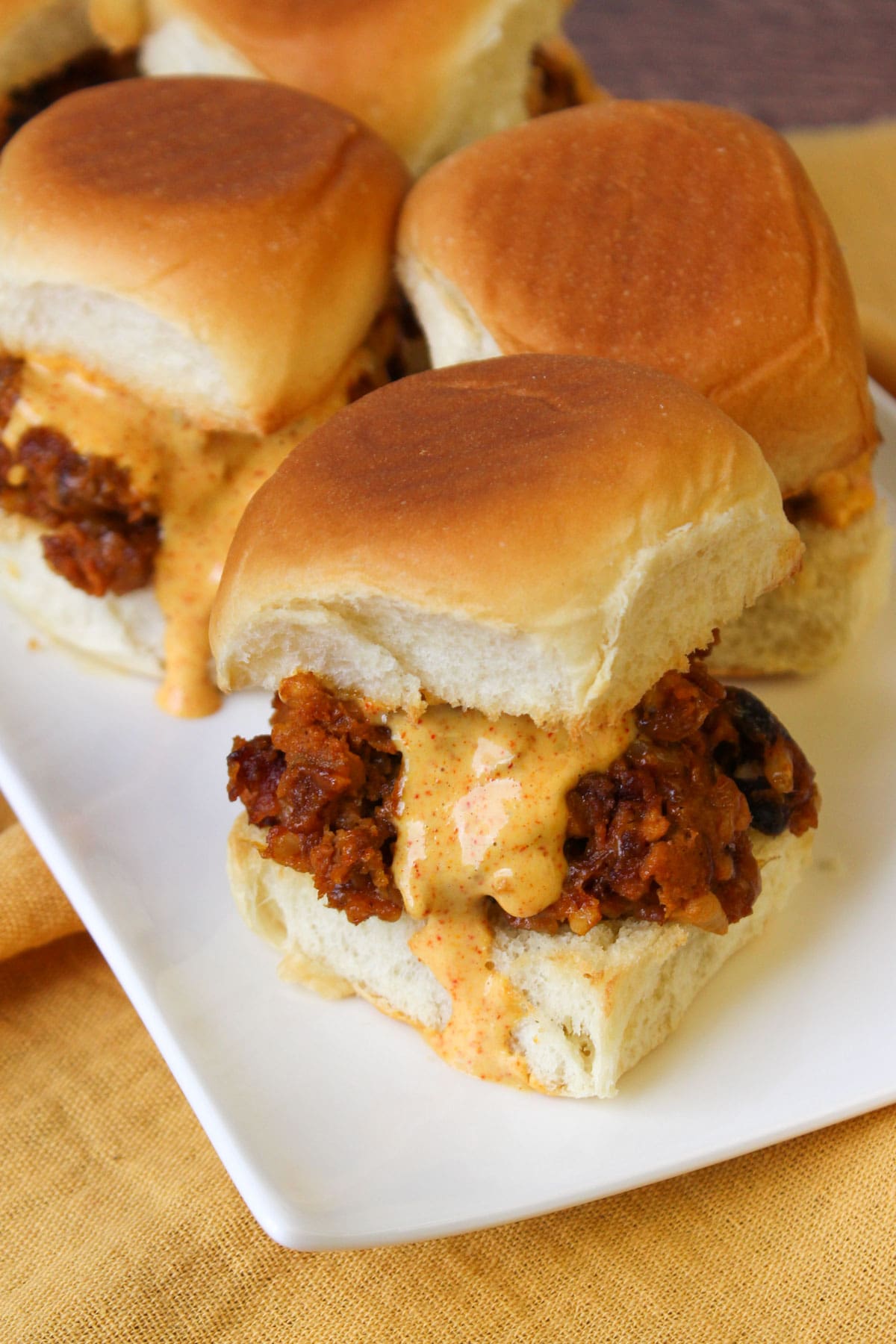A white plate of southwest black bean sliders with chili lime dressing.