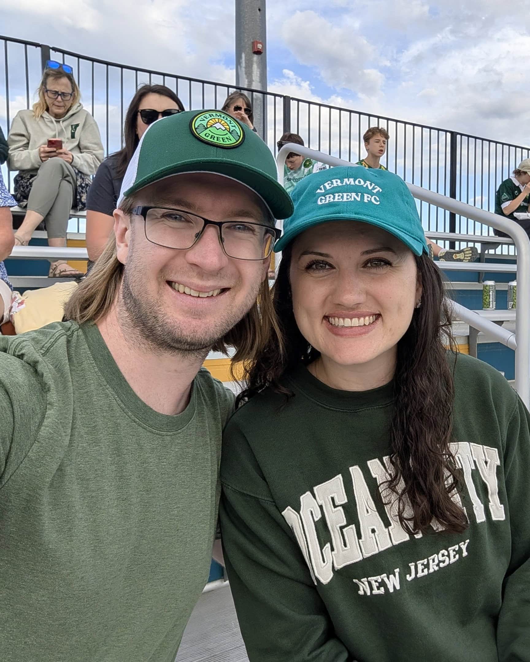 Alex and Nicole smiling in the stands at a soccer game.