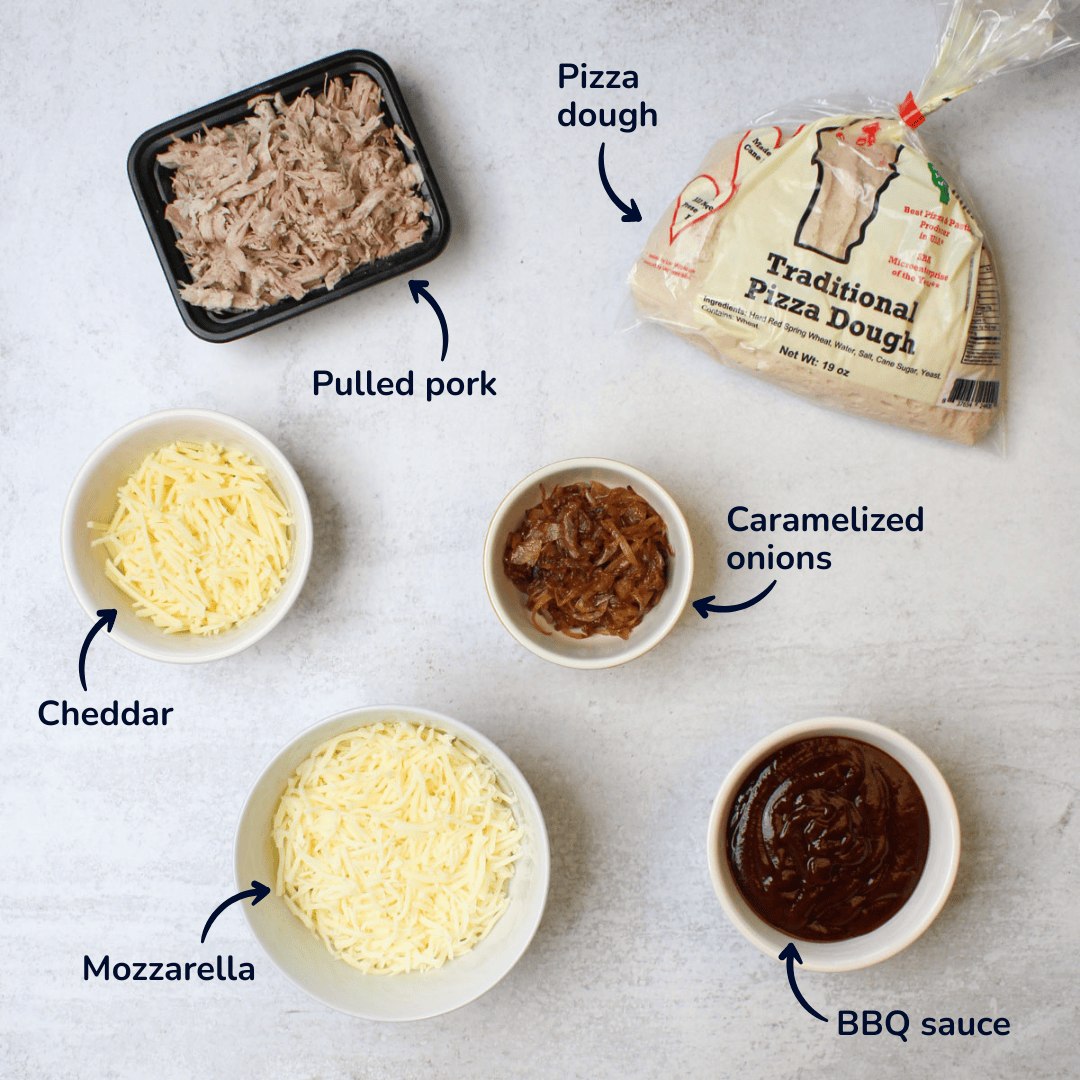 Ingredients for barbecue pulled pork pizza: pizza dough, pulled pork, caramelized onions, cheddar, mozzarella, and barbecue sauce.