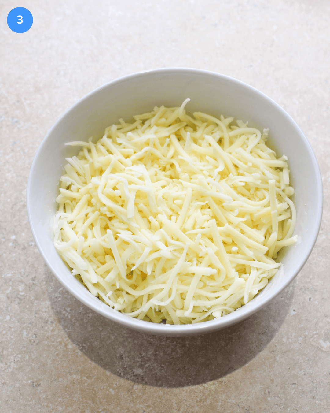 A white ceramic bowl of shredded cheese.