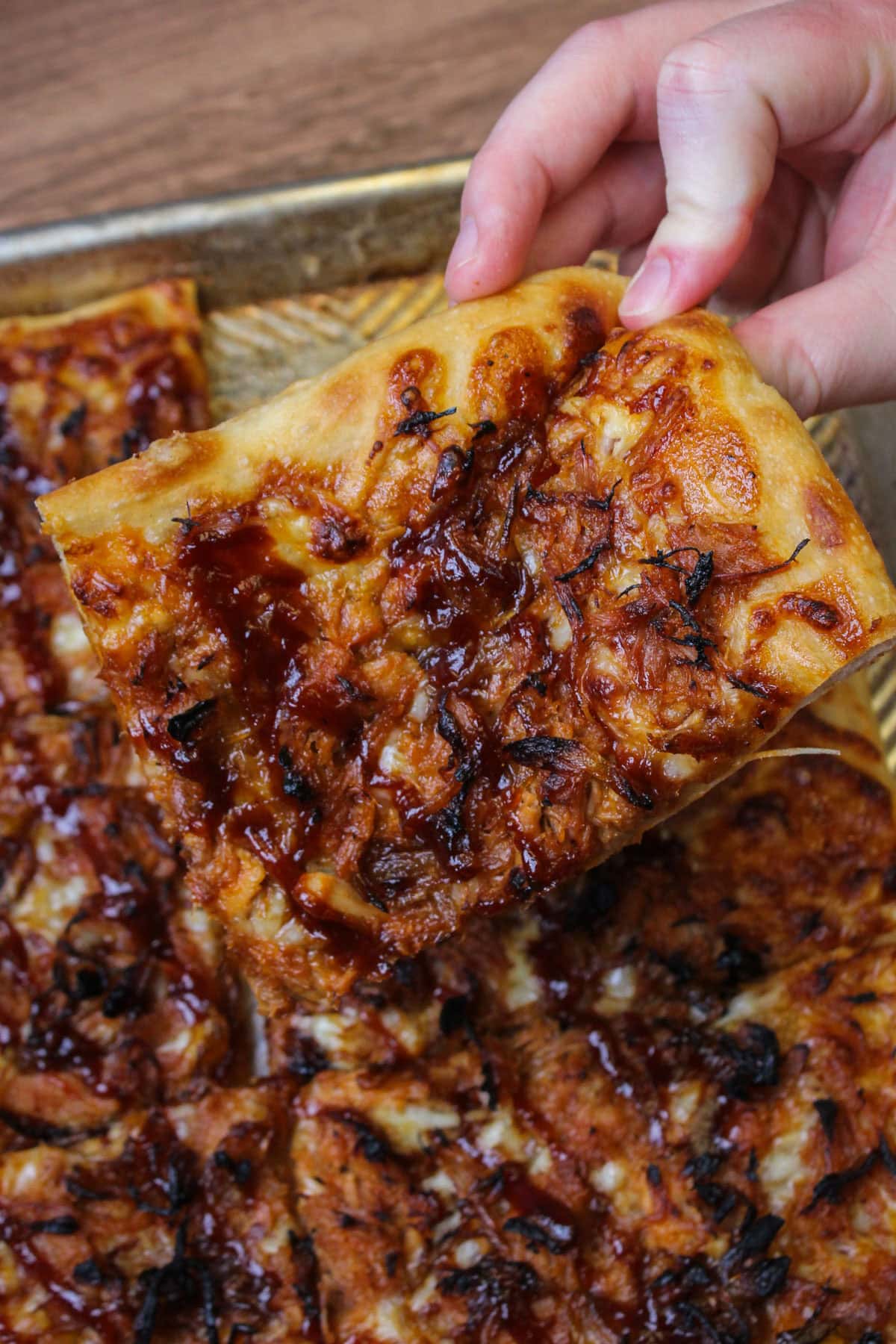 A square corner slice of barbecue pulled pork pizza.