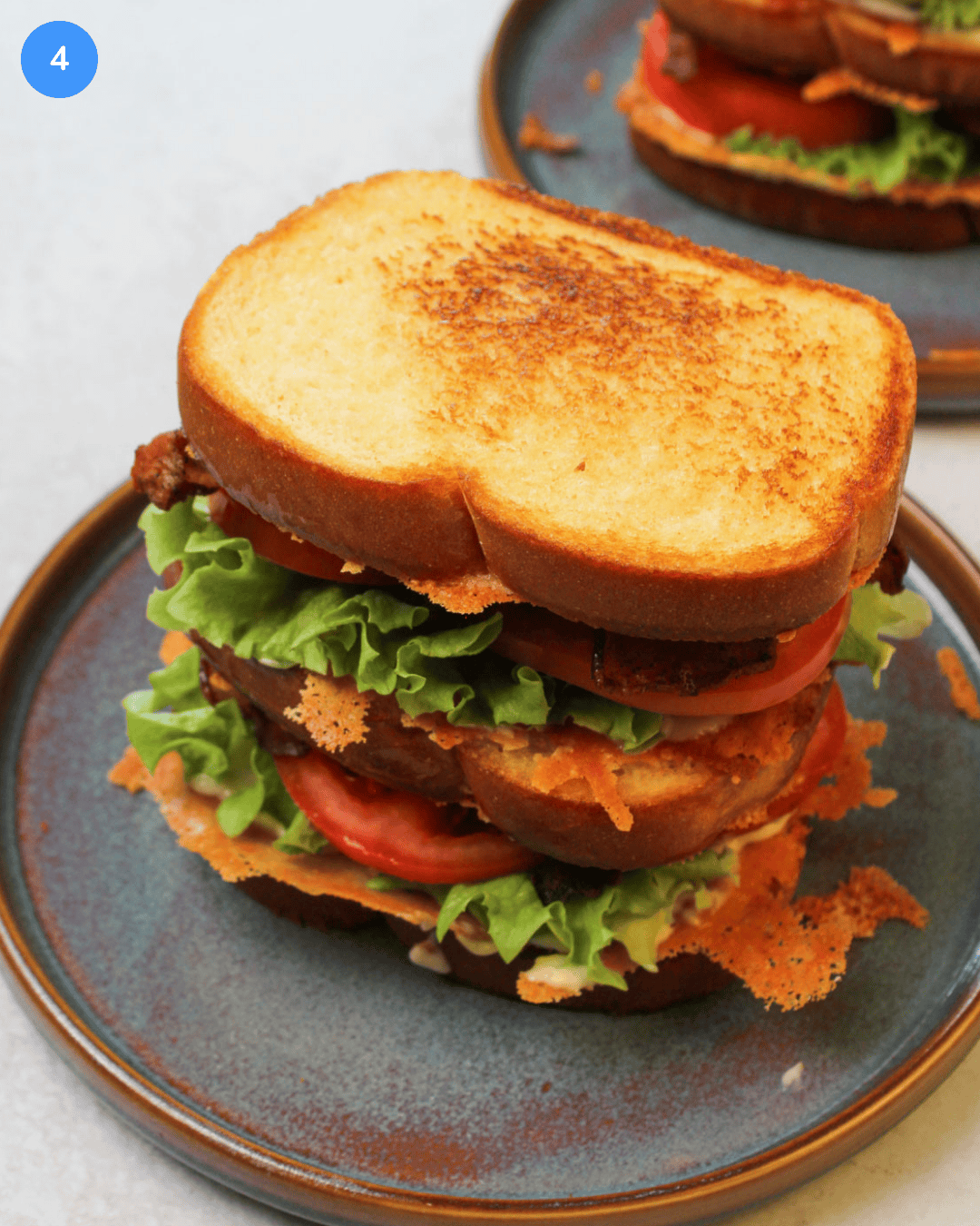 A freshly made blt club sandwich on a blue stone plate.