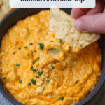 A tortilla chip dipped in buffalo artichoke dip with a title overlaid.