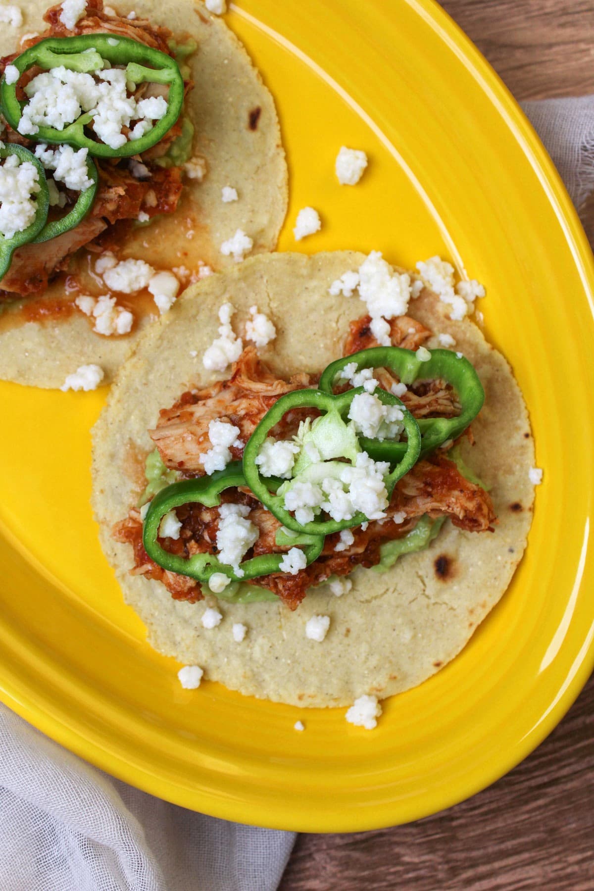 A bright yellow plate of chicken tinga tacos on homemade corn tortillas.