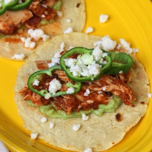 A freshly made chicken tinga taco with anaheim pepper wheels, queso fresco, and mashed avocado.