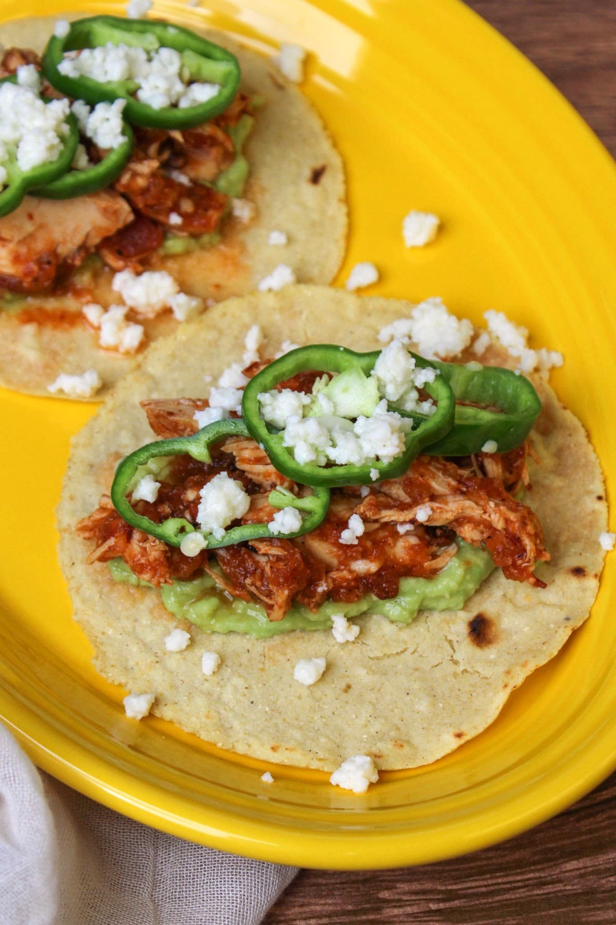 A freshly made chicken tinga taco with anaheim pepper wheels, queso fresco, and mashed avocado.