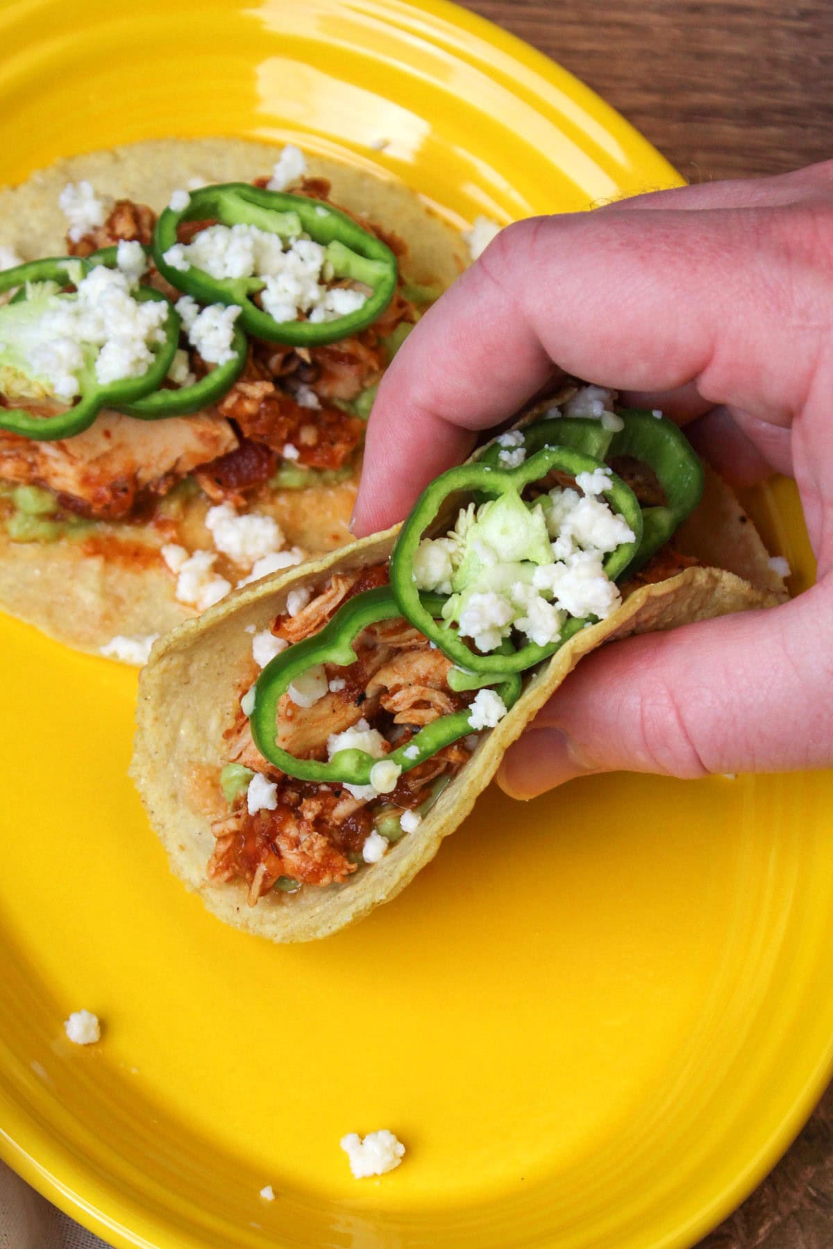 A hand picking up a freshly made chicken tinga taco.