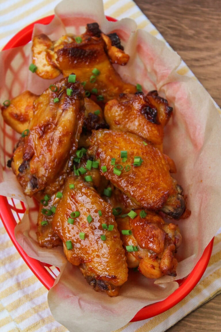 A red basket of chili lime chicken wings, lined with parchment paper.