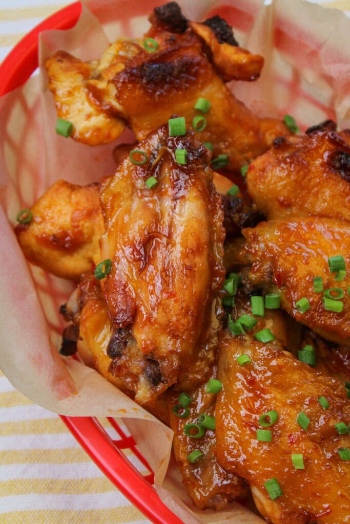 A basket of freshly baked chili lime wings garnished with chives.