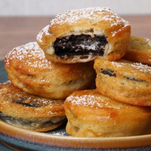 A pile of freshly made fried oreos on a blue stone plate.