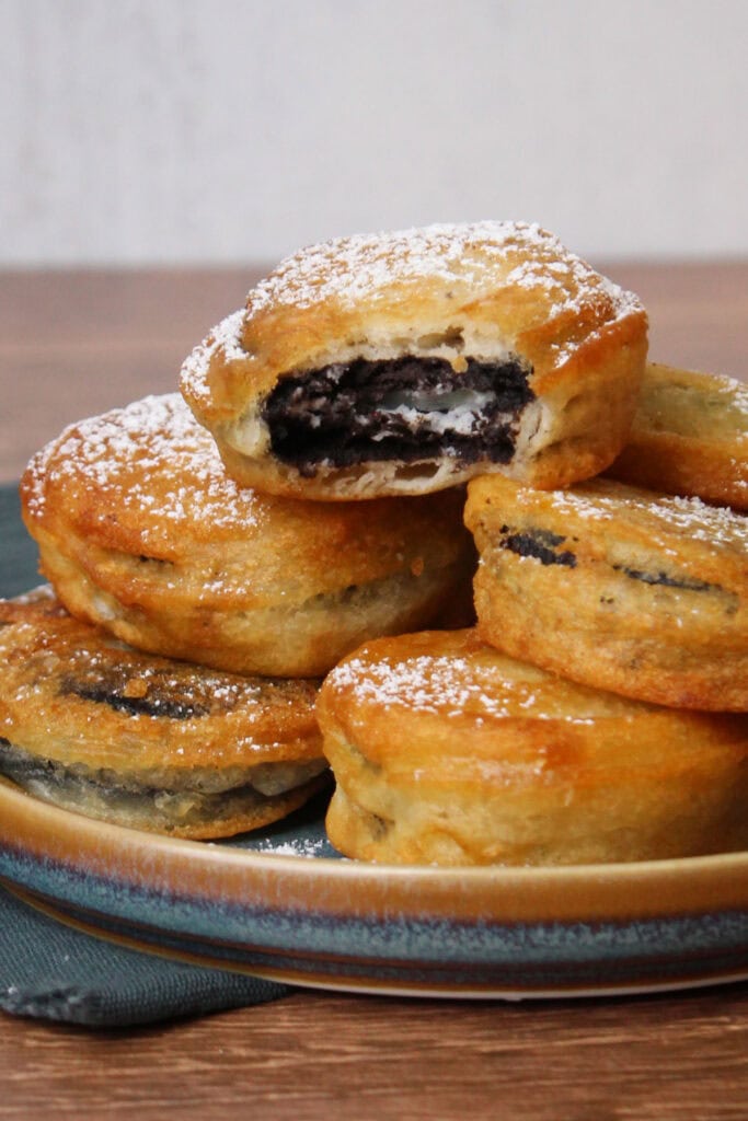 A pile of freshly made fried oreos on a blue stone plate.